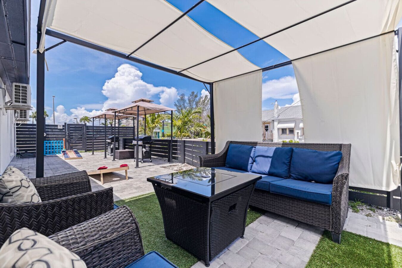 Une terrasse extérieure aménagée avec des meubles en osier, une table en verre et un espace barbecue.