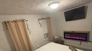 Un dormitorio con cama, televisor de pantalla plana en la pared y chimenea.
