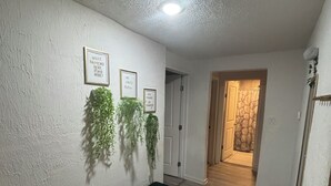 Un pasillo con un banco, citas enmarcadas y plantas colgantes.