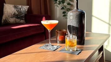 A wooden table with a martini glass, a shot glass, and a bottle of whiskey.