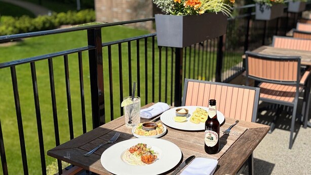 An outdoor dining area with a table set for two, featuring plates of food, a bottle of beer, and a glass of water. - TheHillbrookSherborne (Sherborne)