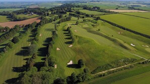 An aerial view of a golf course with multiple holes, trees, and open fields. - TheHillbrookSherborne (Sherborne)