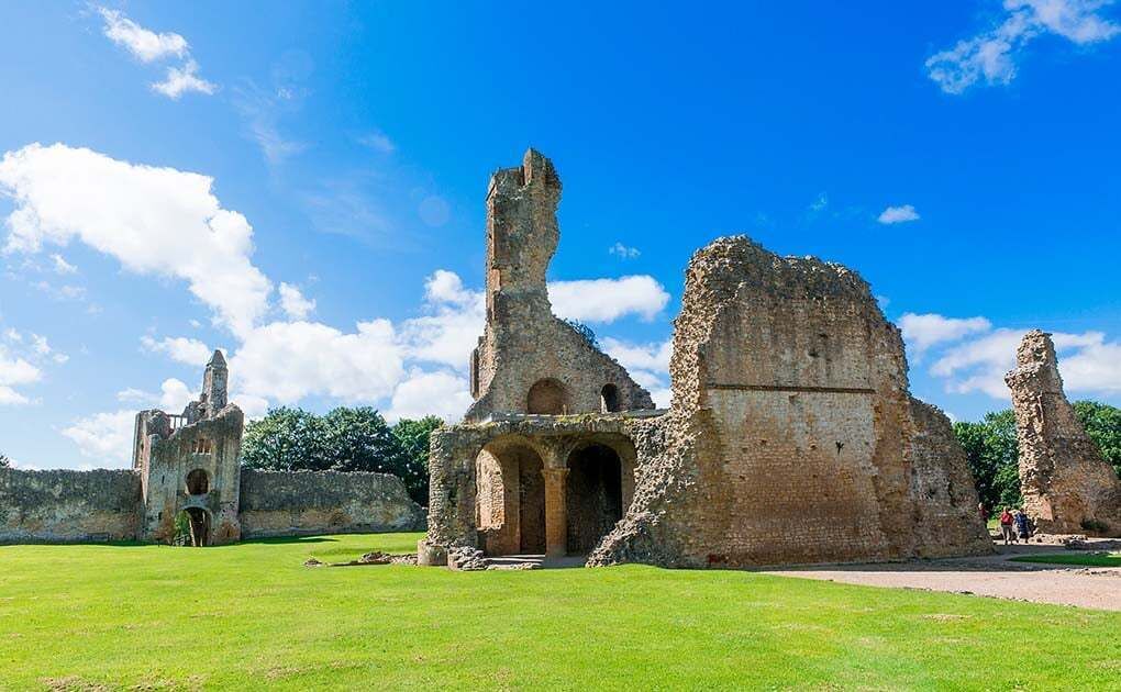 Ancient ruins with arches and a tower, set against a clear sky.