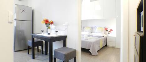 Une cuisine compacte comprenant un réfrigérateur, une table à manger avec des chaises et un petit banc.