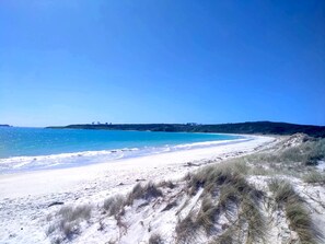A beach with white sand and clear blue water.