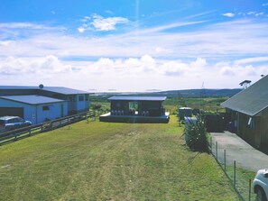 A property with a large open yard, a guesthouse, and a main building with a garage.