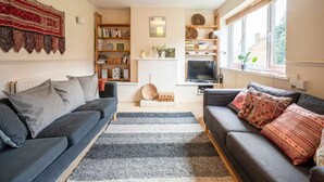 A living room with two sofas, a fireplace, a TV, and a bookshelf.