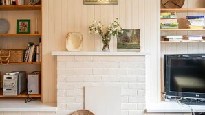 A living room with a fireplace, bookshelves, a flat-screen TV, and decorative items.