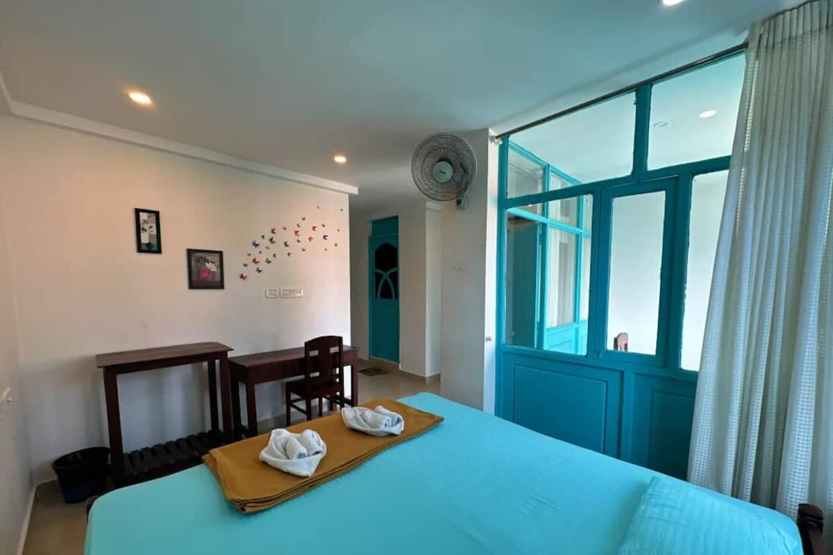 A hotel room with a bed, a desk, a chair, and a window with curtains.