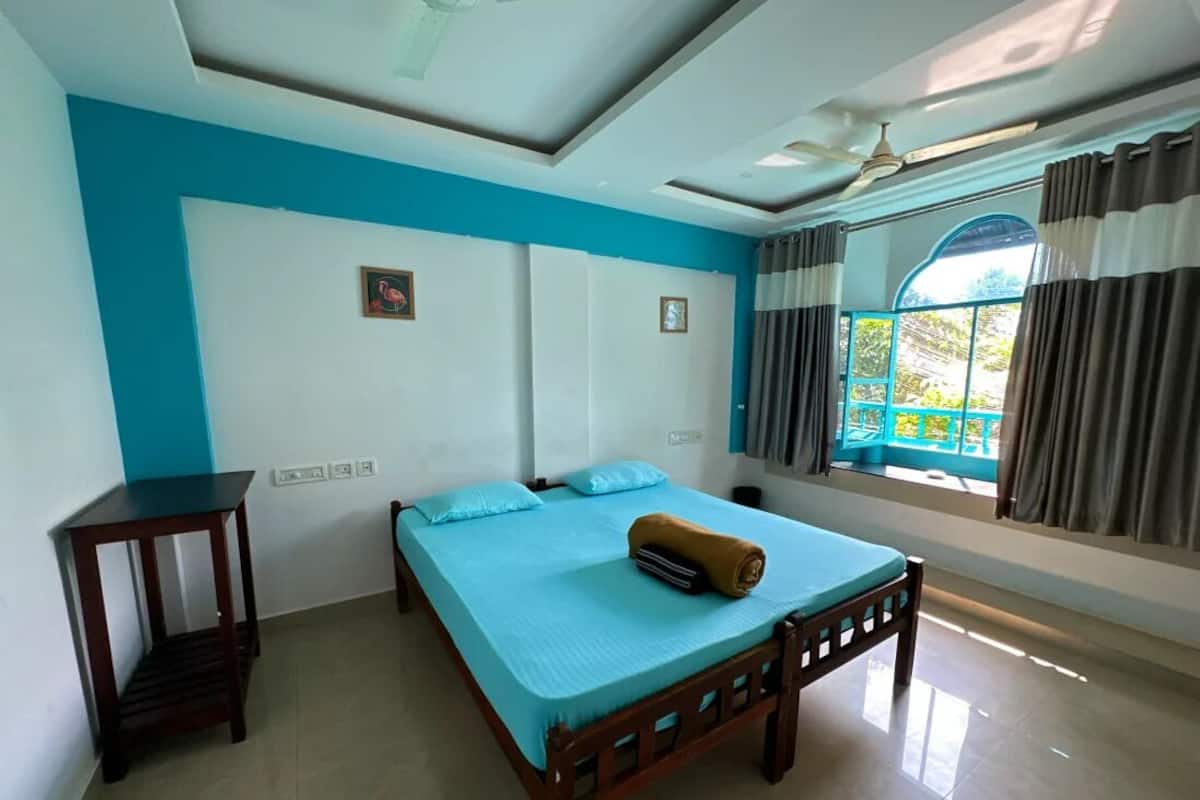 A bedroom with a bed, a nightstand, a ceiling fan, and a window with curtains.