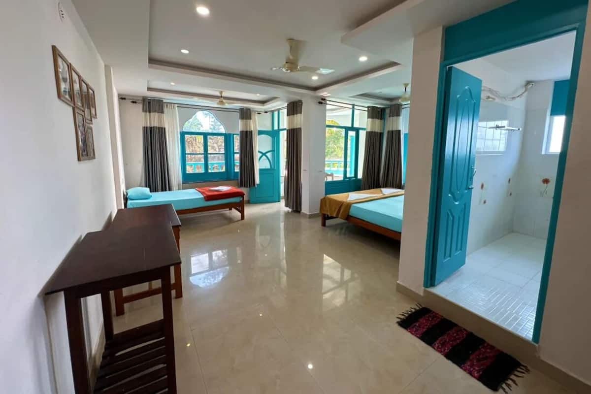 A hotel room with a bed, a desk, a chair, and a bathroom with a shower.