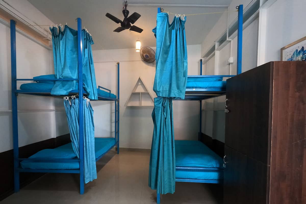 A room with bunk beds, a ceiling fan, and a wall-mounted fan.