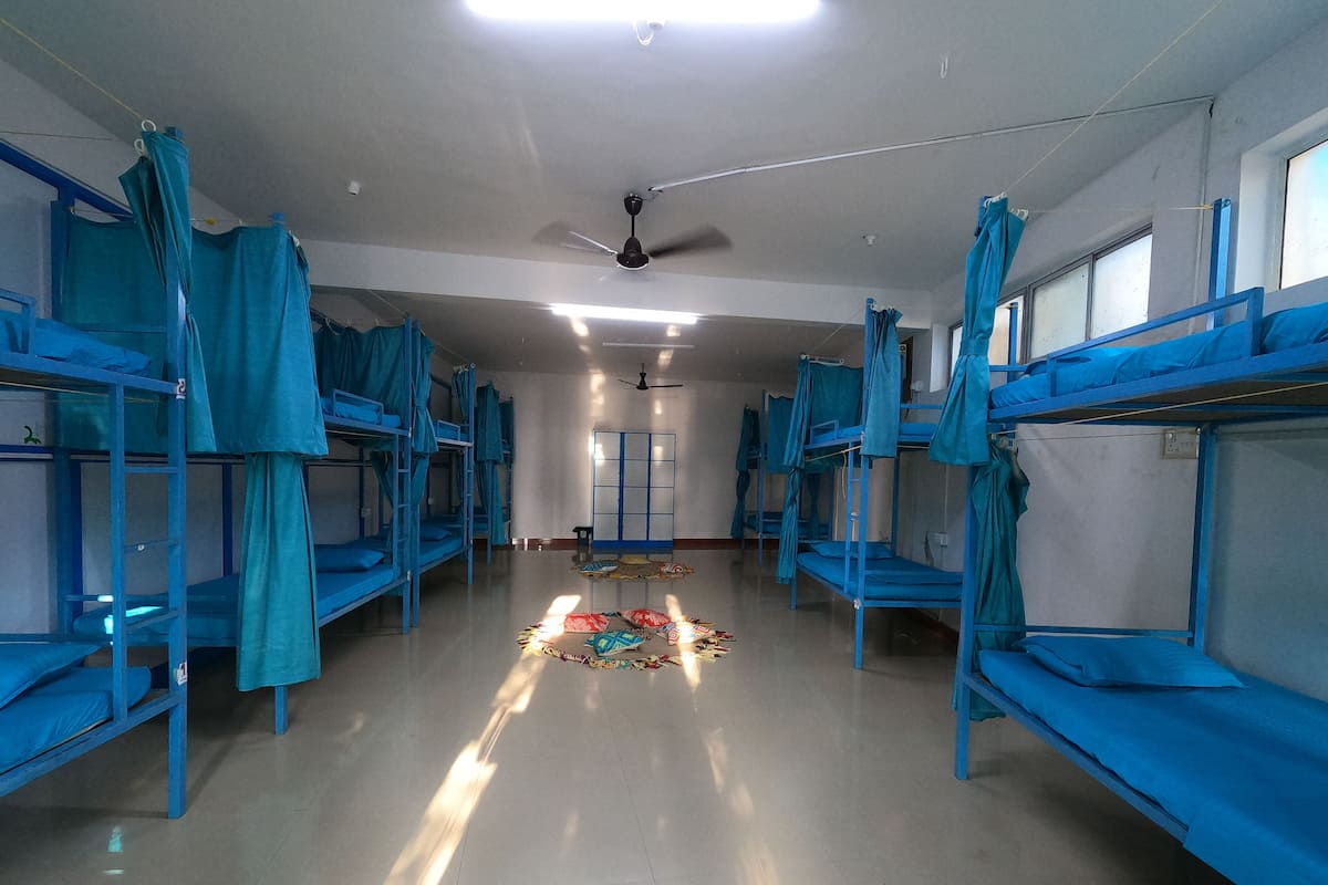 A dormitory room with bunk beds, a ceiling fan, and a window.