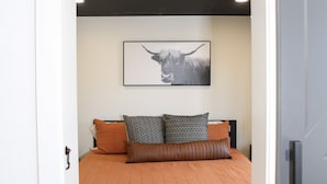 A bedroom with a bed, pillows, a rug, and a wall-mounted picture. - Newly-remodeled cozy condo, downtown Manhattan, MT! (Manhattan)