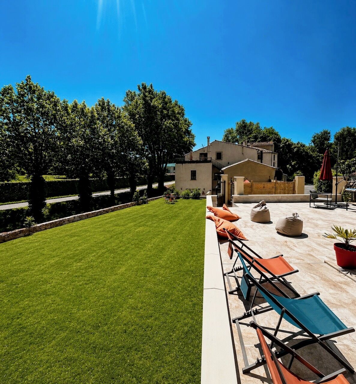 A well-maintained lawn, outdoor seating area with chairs and cushions, and a building with a flat roof.