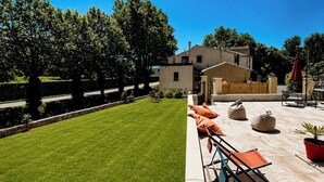 A well-maintained lawn, outdoor seating area with chairs and cushions, and a building with a flat roof.