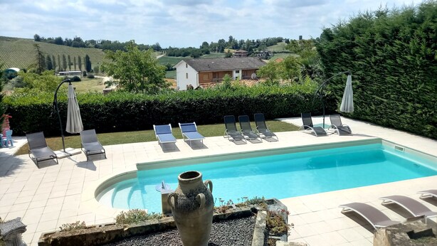 Una piscina con sillas de descanso y una urna decorativa.