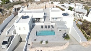 En modern villa med en swimmingpool, en täckt uteplats och utsikt över havet.