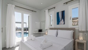 Ett modernt hotellrum med en stor säng, ett nattduksbord med en lampa, utsikt över en swimmingpool och en tavla på väggen.