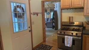 A kitchen with wooden cabinets, a stainless steel stove, and a door with a window.