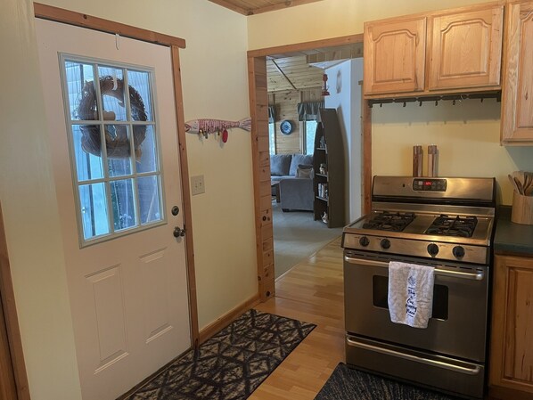 Una cocina con gabinetes de madera, una estufa de acero inoxidable y una puerta con ventanal.