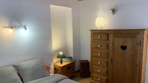 A bedroom with a bed, a dresser, a nightstand, a lamp, and a wall-mounted light fixture. - Ancienne Bergerie en Pleine Nature Dans le Vercors (Rencurel)