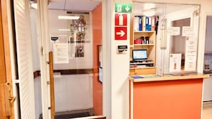 An office space with a reception desk, computer, and shelves with binders.