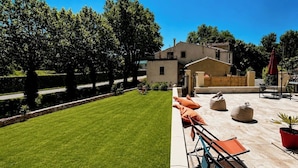 A well-maintained lawn, outdoor seating area with chairs and cushions, and a building with a flat roof.