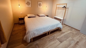 A bedroom with a bed, two bedside tables, a wardrobe, and wall art.