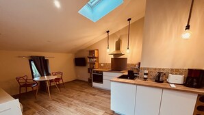 A compact kitchen with a skylight, a dining area with chairs, and a coffee maker.