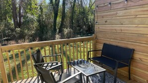 Eine Holzterrasse mit Tisch, Stühlen und einer Bank, dazu ein gemustertes Teppich.