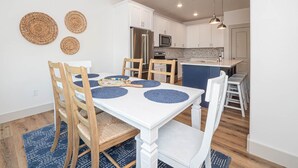A modern kitchen with white cabinets, stainless steel appliances, and a blue island.