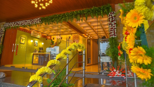A hotel lobby with a reception desk, a staircase with yellow flowers, and a ceiling light fixture. - Aero Hotel Near Bangalore International Airport (Bengaluru)