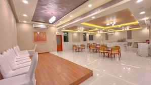 A spacious conference room with a wooden table and white chairs, equipped with ceiling lights and an air conditioning unit. - Aero Hotel Near Bangalore International Airport (Bengaluru)