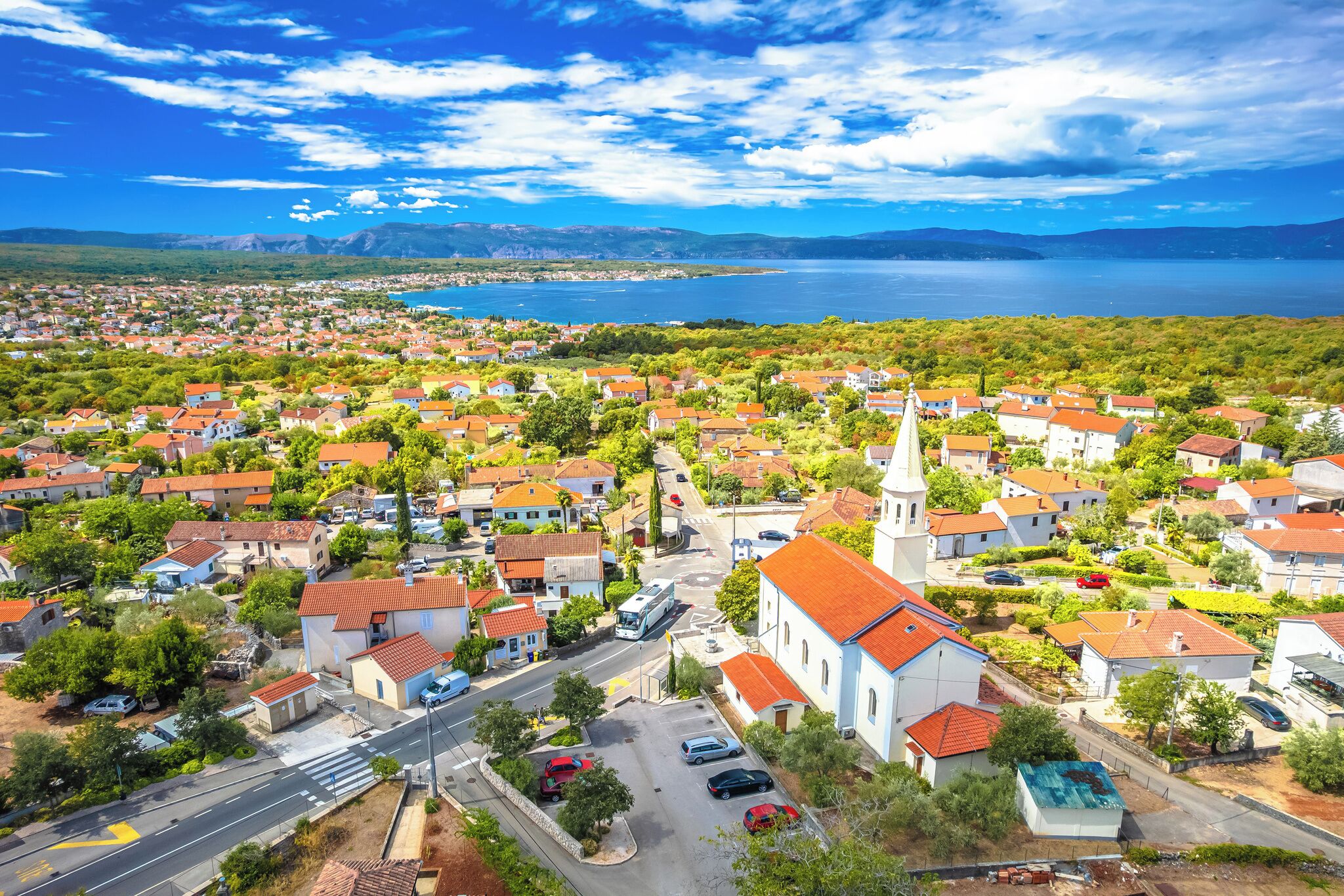 A coastal town with a prominent church, residential buildings, and a clear view of the sea.