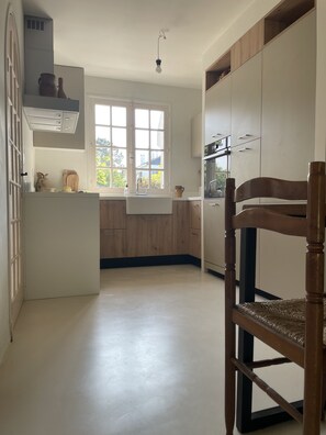 Een moderne keuken met houten kastjes, een wit aanrechtblad en een raam dat natuurlijk licht binnenlaat.