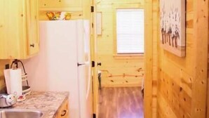 L’intérieur d’une cabane en bois comprend un coin cuisine équipé d’un réfrigérateur, d’un évier et d’un plan de travail en granit.