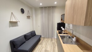 Un espace de vie compact comprenant un canapé, une kitchenette et un rideau séparant l’espace repas du coin salon.