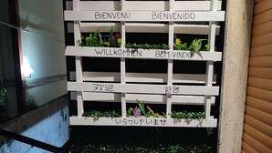 Une structure en bois peinte en blanc, ornée de plusieurs panneaux d’accueil rédigés dans différentes langues.