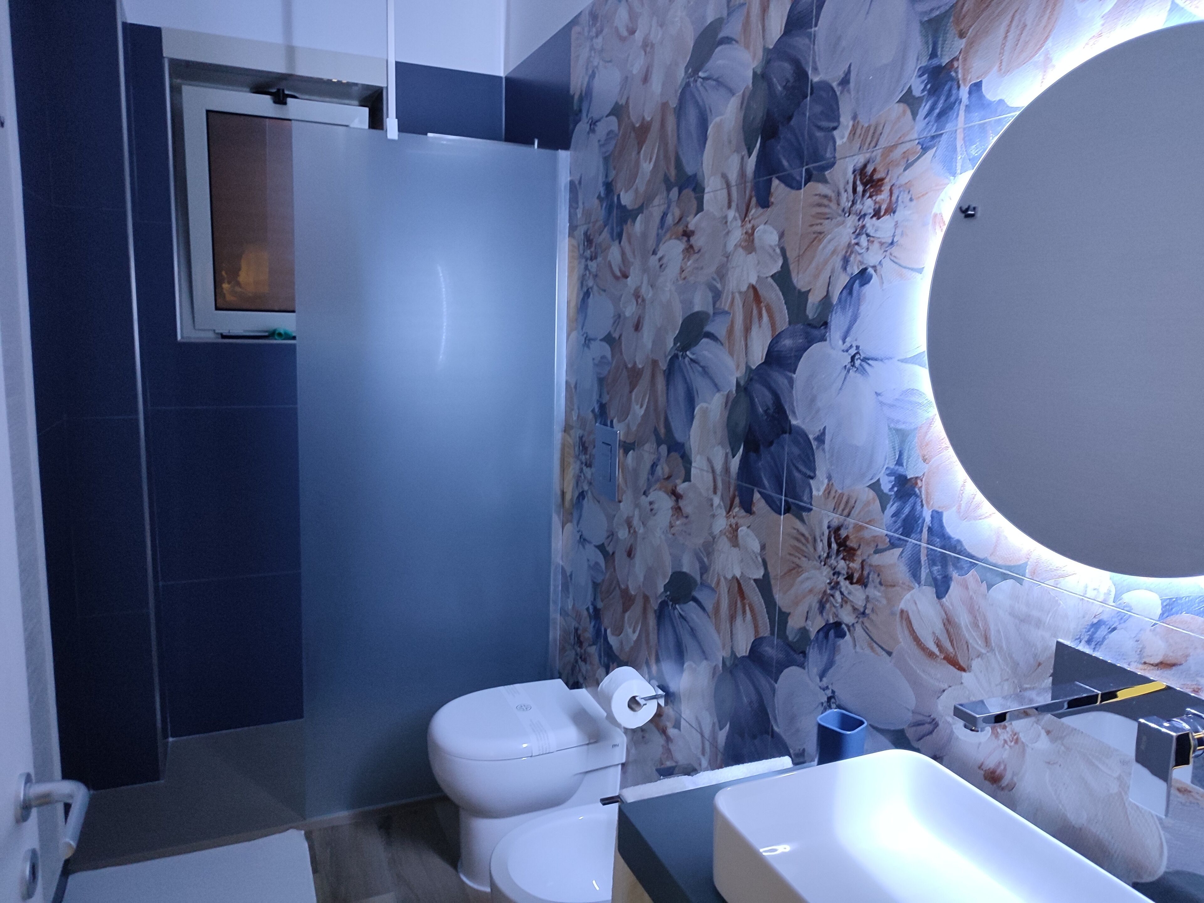 A modern bathroom with a toilet, sink, and a large mirror.