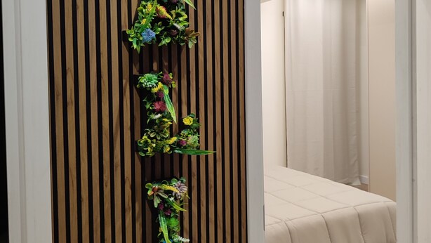 Une pièce avec un lit, un mur recouvert de lambris en bois et un jardin vertical.