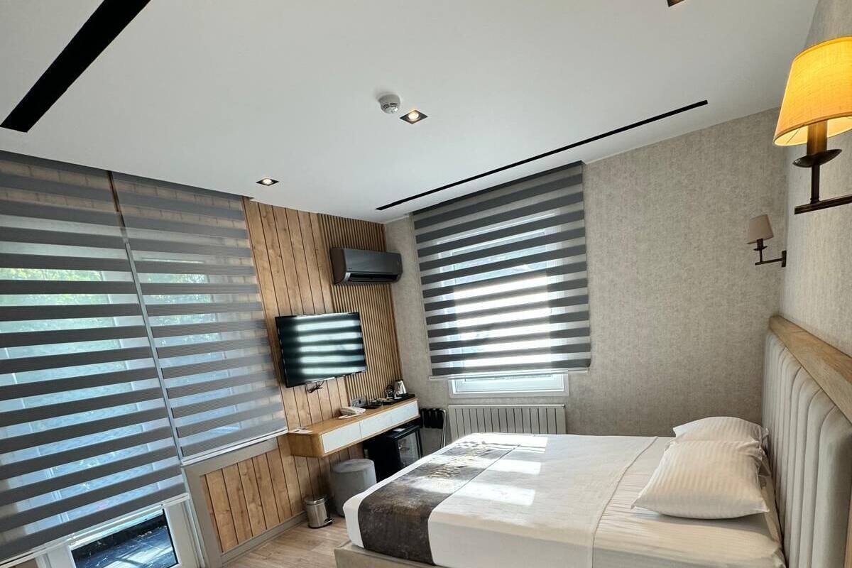A modern bedroom with a large bed, built-in TV, and a wooden bench.