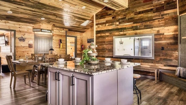A rustic interior with a wooden ceiling, a kitchen area with a marble island, and a cinema sign.