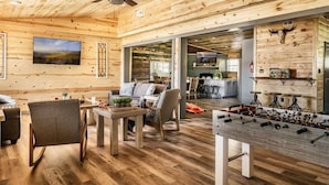 A spacious wooden interior with a foosball table, a sofa, and a dining area.