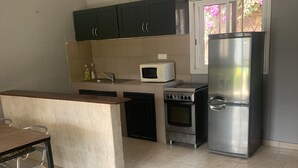 Una cocina compacta con armarios oscuros, microondas, estufa y refrigerador.