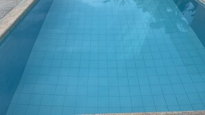 Una piscina rectangular con suelo de baldosas y escalones de acceso.
