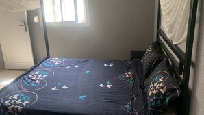 Una cama con un edredón azul oscuro adornado con motivos de mariposas, un dosel y una ventana con cortinas.