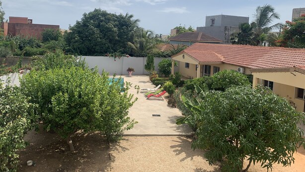 Un patio con piscina, rodeado de vegetación y edificios.