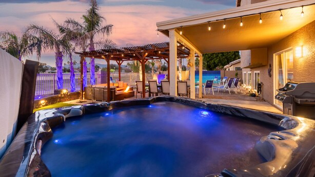 Een hottubgedeelte met een pergola, loungezetels en een zwembad.