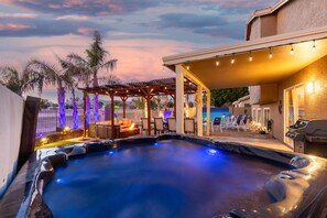 Un área de hidromasaje con una pérgola, sillones de descanso y una piscina.